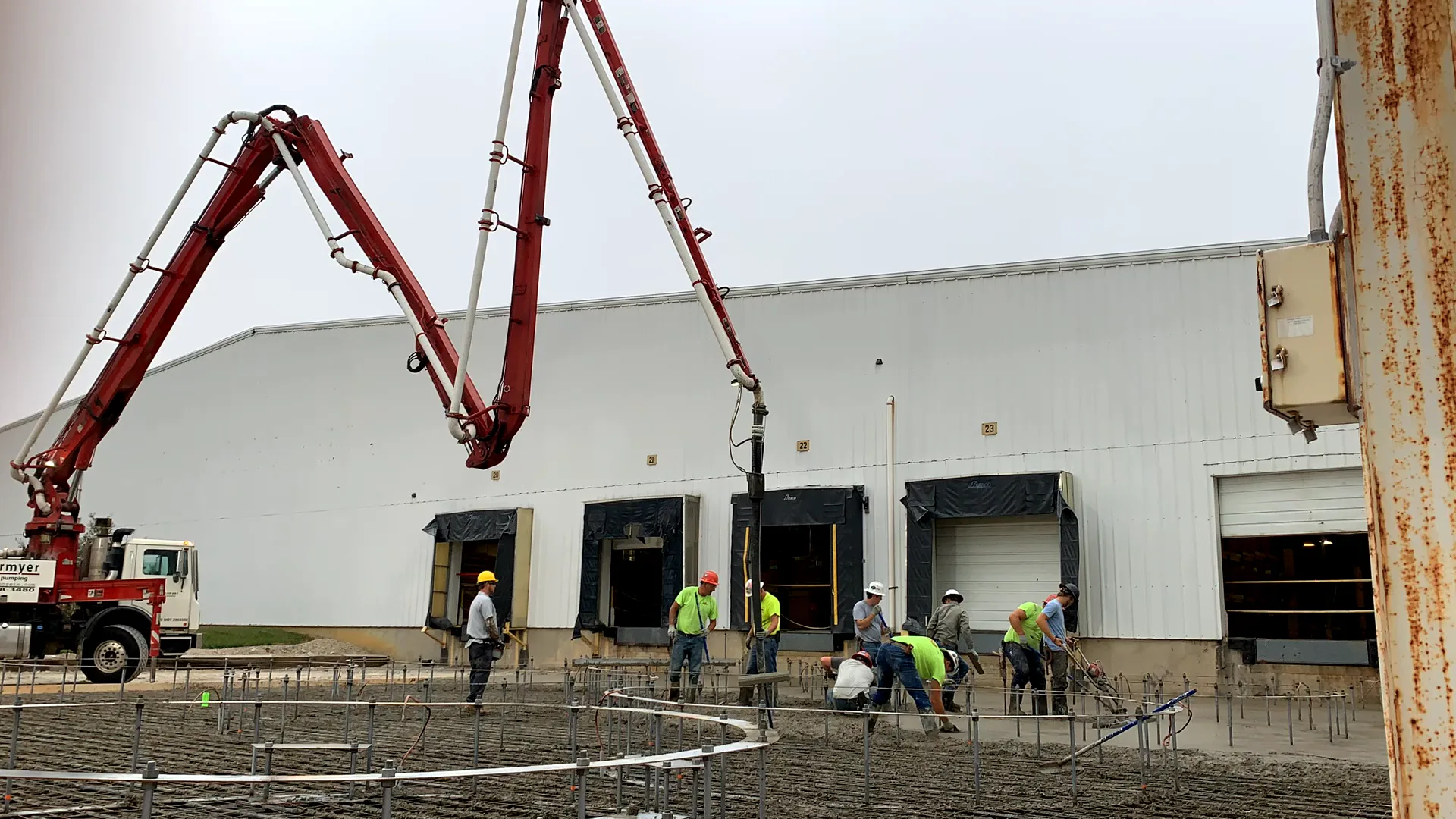 Employees laying concrete outside of a warehouse shipping dock